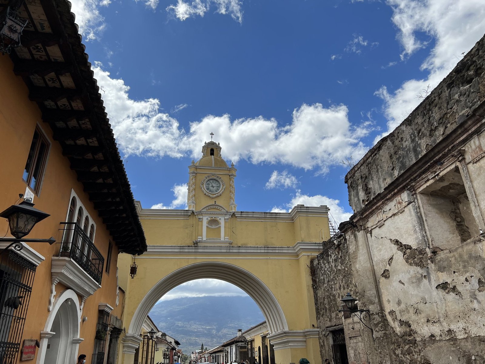 The yellow Santa Catalina Arch in Antigua, Guatemala, with a volcano framed beneath it