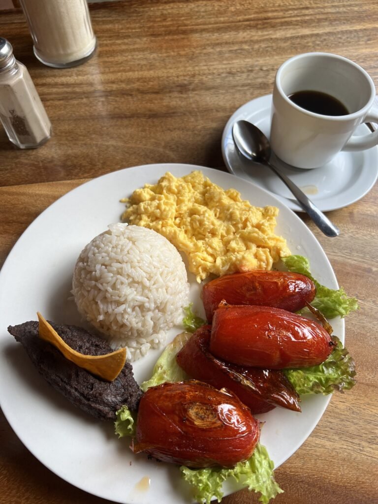 A traditional Guatemalan breakfast of scrambled eggs, rice, black beans, roasted tomatoes and black coffee